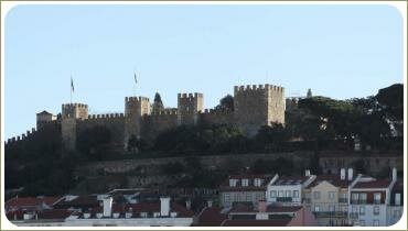 Вид на крыши домов и стены крепости среди пышных деревьев