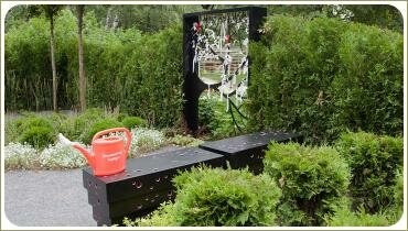 Декоративная ширма и лейка на скамейке в саду