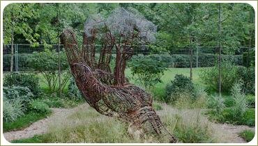 Скульптура в виде руки среди растений