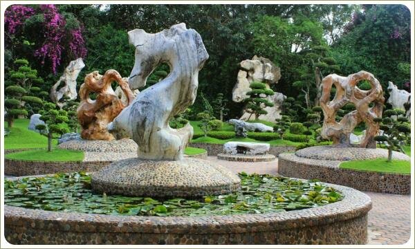 Камень в форме морского конька в центре круглого водоёма облицованного галькой