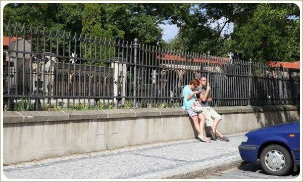 Парочка людей с мороженым на фоне металлического ограждения и зелени