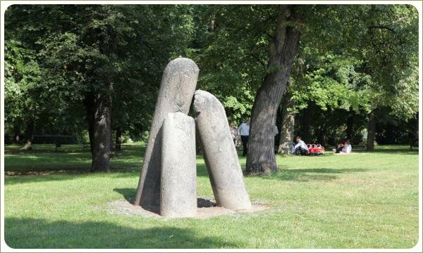 Три каменных столба на зелёной лужайке на фоне больших деревьев