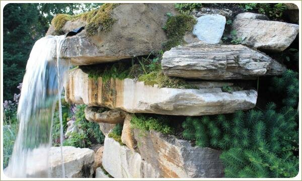 Водопад из крупных камней. Урал Плоские каменные глыбы уложенные друг на друга и растения в расщелинах и поток падающей воды