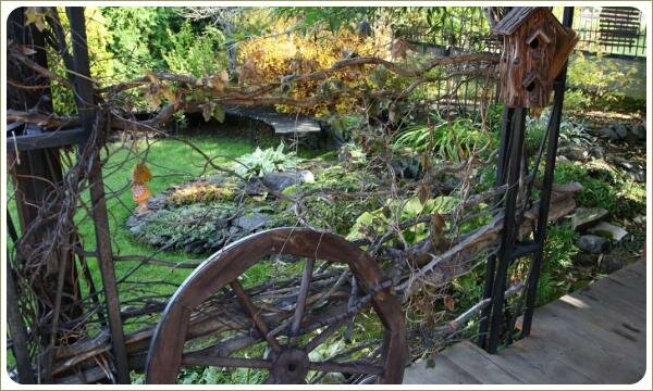 Ограждение из тонких веток и колесо на фоне зелёной лужайки