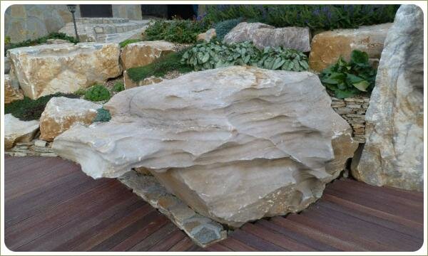 Большой камень с выступом в виде полочки на фоне деревянного мощения