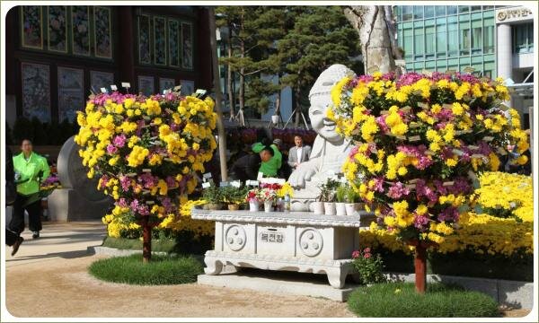 Светлая фигура Будды и композиции из цветов с розовым и жёлтым цветением