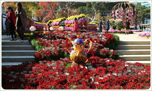 Фигурка с крыльями на фоне волны из красных цветов на ступенях большой лестницы