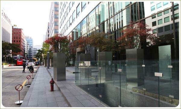 Современные контейнеры. Городское озеленение. Сеул Высокие контейнеры из светлого материала с кусами красноватого цвета на фоне стекла и небоскрёбов