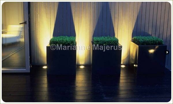 Контейнеры при ночной подсветке и тени на стене на фоне деревянной террасы