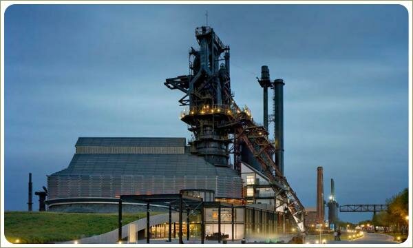 Промышленные металлические конструкции на фоне бетонной дорожки с подсветкой и газонов