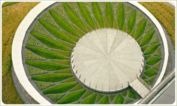 Возвышающееся сооружение круглой формы с круглой площадкой и цветник по окружности и из низкорослых растений