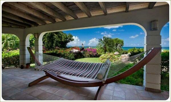 Уютный гамак: под навесом Полосатый гамак на деревянном каркасе на фоне крытого дворика