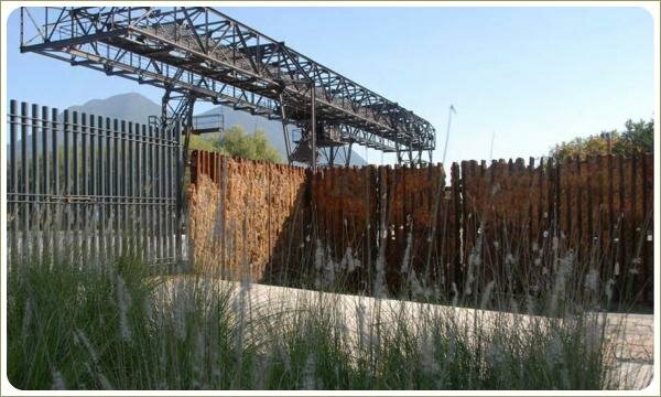 на фоне цветущих злаковых трав ржавая конструция заполненая породой выполняющая роль ограждения