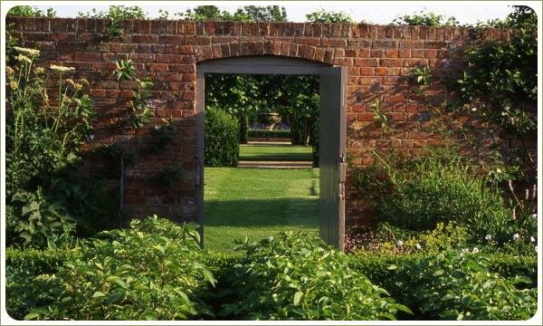 Крпичная стена с дверью и ось по которой просматривается перспектива сада