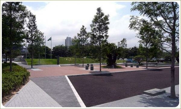 Площадь с покрытием разными материалами и стриженые кустарники и штамбовые деревья и зелёный холм