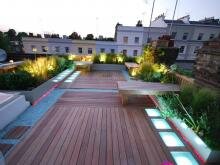 Простые скамейки на деревянном покрытии и приподнятые цветники и гравийная отсыпка