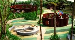 На поверхности из прорезиненного покрытия различные огороженные зоны для детей и деревья