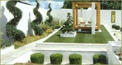 Стриженные в разные формы деревья и кустарники и простая беседка в виде перголы и прямоугольные формы