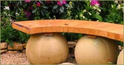 Скамейка на сферах на фоне цветника и каменной отсыпки