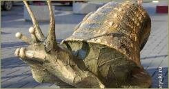 Огромная улитка из металла цвета бронзы на мощёной плиткой площади