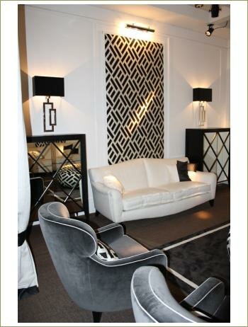 Светлый классический интерьер, белые стены, белый диван и серое кресло, на стене панно с черно-белым геометрическим рисунком, 2 черные бра