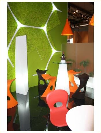 Зеленая стена, черный блестящий пол, необычной формы мебель, напольные белые светильники 