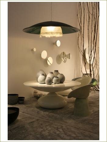 Белый интерьер, стол круглой формы, большая черная люстра в виде тарелки, круглые зеркала на стене