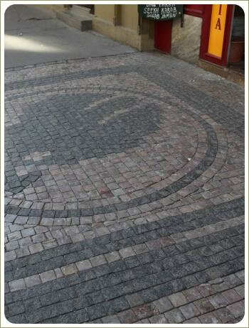 Пражские орнаменты - мощение брусчаткой тротуаров Орнамент с кругом и рисунком в его центре из небольшого камня разных оттенков серого